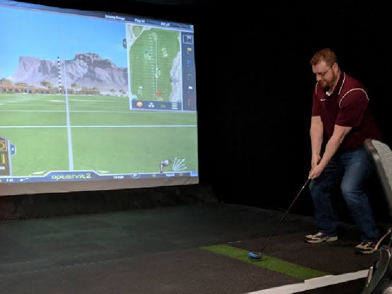 a guy playing golf on a simulator