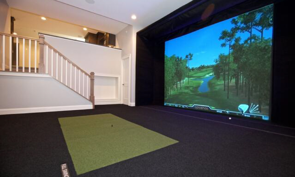 golf simulator setup with a hitting mat placed in front of a screen enclosure